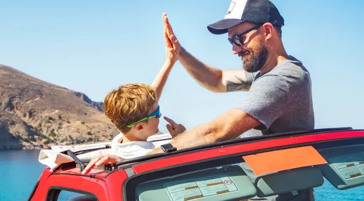 Vater und Kind machen High-Five im Auto.