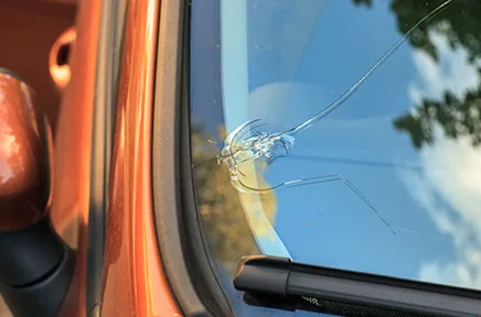 "Ein Steinschlag hat eine sternförmige Beschädigung in der Windschutzscheibe eines orangefarbenen Fahrzeugs verursacht.