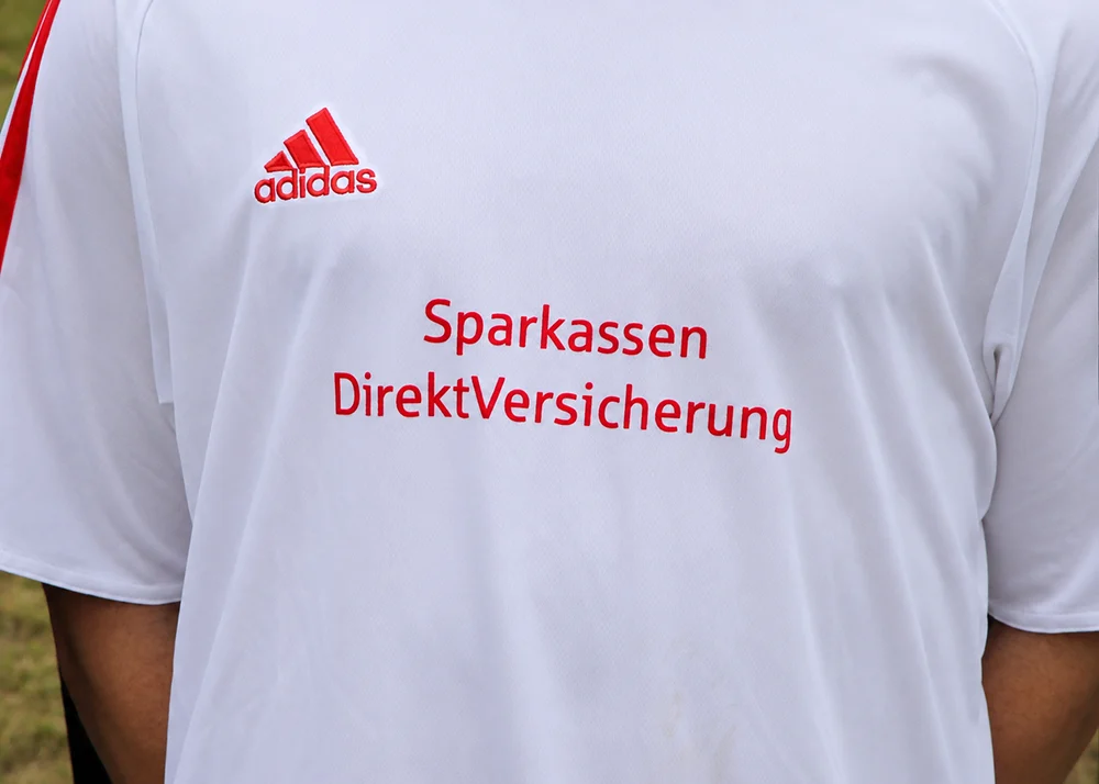 Ausschnitt weißes Sportshirt mit Aufschrift Sparkassen DirektVersicherung